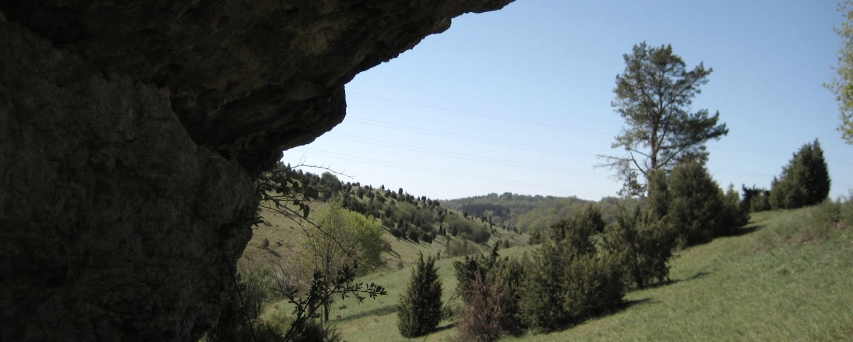 Rocky outcrop in the foreground, green hilly landscape with trees and blue sky in the background., © Touristik GmbH Gerolsteiner Land