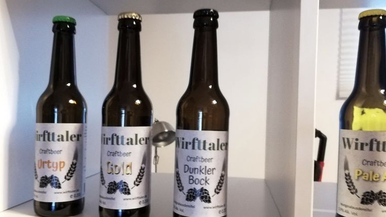 Ein weißes Regal, in dem in mehreren Fächern Bierflaschen unterschiedlicher Sorten der Marke "Wirfttaler" stehen.