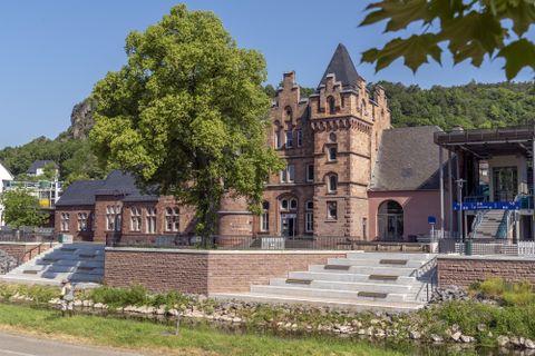 Historisches Gebäude in Gerolstein mit markantem Turm, umgeben von Bäumen und Grünflächen. Klare, sonnige Wetterbedingungen.