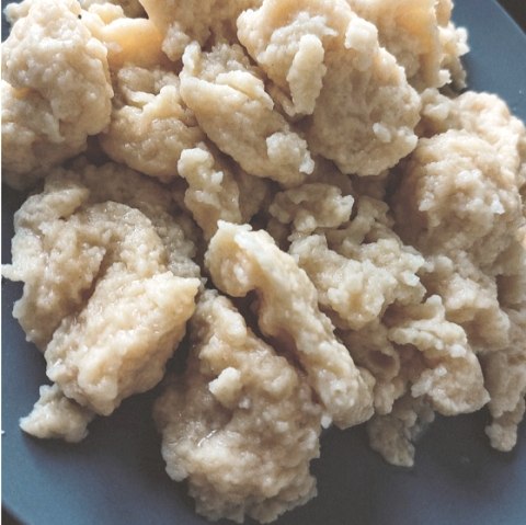 Several differently shaped dough dumplings are stacked on top of each other in a bowl.