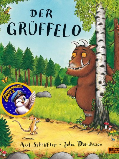 Grüffelo befindet sich mit einer kleinen Maus in einem Wald, er hält sich an einem Baum fest und lächelt, auf dem Poster seht "Der Grüffelo - Puppentheaterspatz - Axel Scheffler - Julia Donaldson"