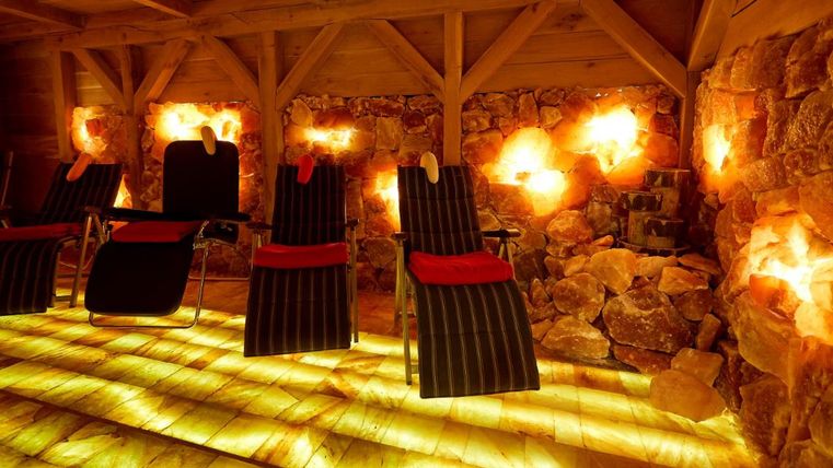 Ein entspannender Raum mit Liegen und salzgefüllten Wänden. Sanftes Licht schafft eine ruhige Atmosphäre.