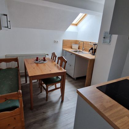 Une cuisine confortable avec une table en bois et des chaises. Les pièces sont lumineuses et aménagées de manière moderne.
