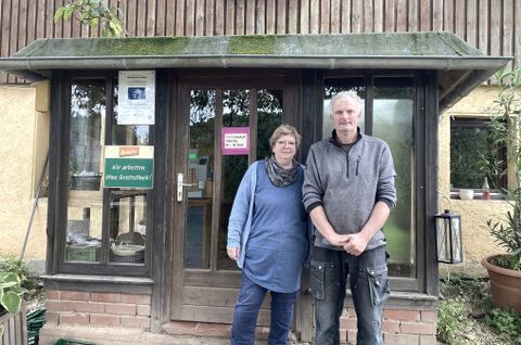 Ein Mann und eine Frau stehen vor einem Gebäude und lächeln in die Kamera.