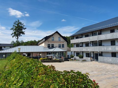 A modern building named "EifelAdventures" in a green environment. The sky is clear and blue, creating an inviting atmosphere.