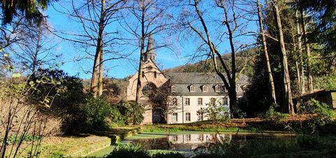 Ein schönes Gebäude umgeben von Bäumen und einem ruhigen Teich. Der klare blaue Himmel sorgt für eine friedliche Atmosphäre.