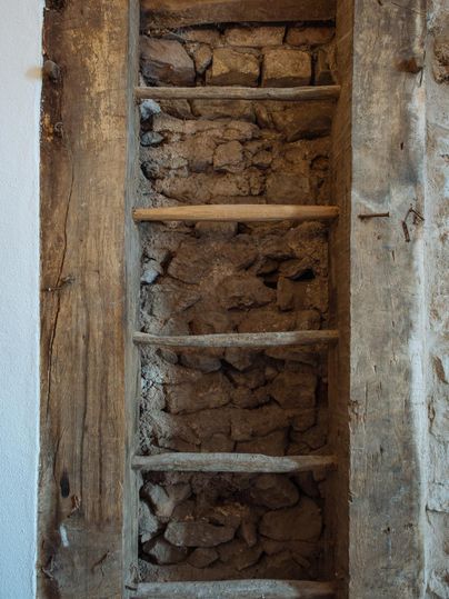 Eine alte Holzleiter, die an einer Wand aus groben Steinen lehnt. Die Leiter ist leicht abgenutzt und hat einen rustikalen Charme.