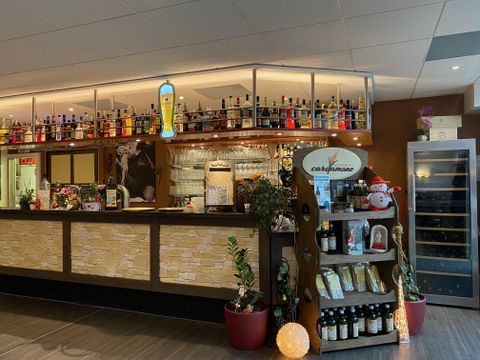 Innenansicht des Restaurants mit Bar, Regalen voller Flaschen und Dekorationen.