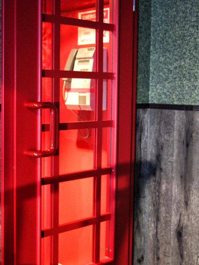 Une cabine téléphonique rouge avec des fenêtres en verre. À l'intérieur se trouve un téléphone.