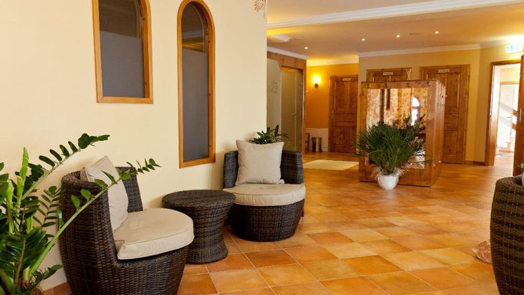 Ein einladender Innenraum mit gemütlichen Rattanmöbeln und Pflanzen. Der Boden ist aus warmen Fliesen, der Raum wirkt freundlich und entspannend.