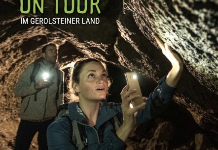 Cover page of the brochure &lsquo;On Tour in Gerolsteiner Land&rsquo; with a cover photo of two hikers in a dark cave.