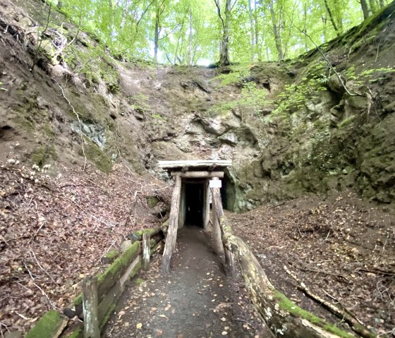 Ein h&ouml;lzerner Stolleneingang im Arensberg Vulkansteinbruch, umgeben von Felsen und Laub. Ein Schild warnt vor Betreten auf eigene Gefahr., &copy; Touristik GmbH Gerolsteiner Land