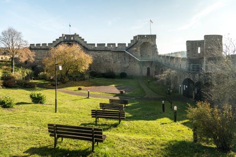 Un château impressionnant entouré de prairies vertes et d'arbres. Des bancs invitent à la contemplation et offrent une vue sur l'architecture historique.