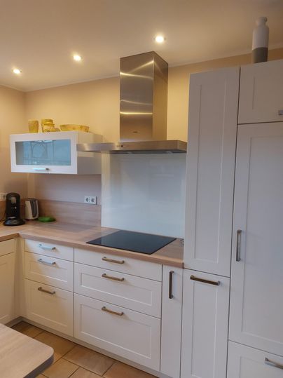 Une cuisine moderne avec des armoires blanches et une hotte. La pièce dispose d'une atmosphère lumineuse et d'appareils fonctionnels.