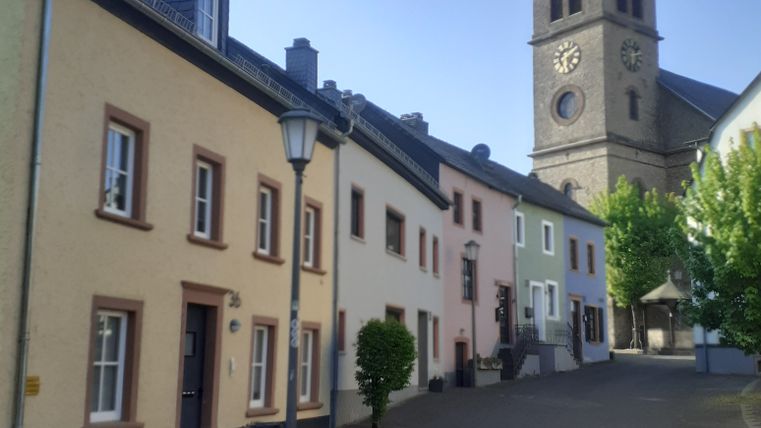 Straße mit bunten Häusern und einer Kirche im Hintergrund.