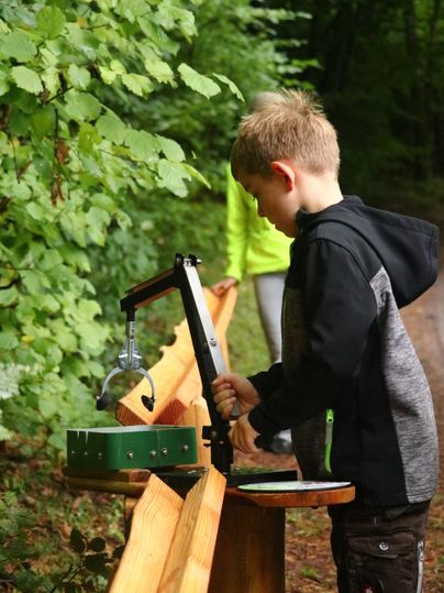 Eine Junge spielt an einem Bagger-Element an einer Holzkugelbahn.