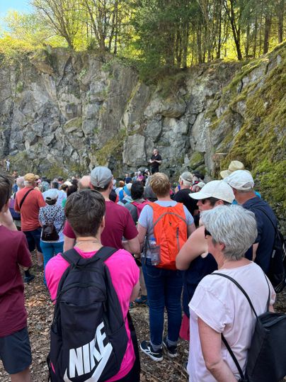 Zahlreiche Wanderer vor einer massiven Steinwand. Der Tourguide erzählt über die geologischen Gegebenheiten vor Ort.