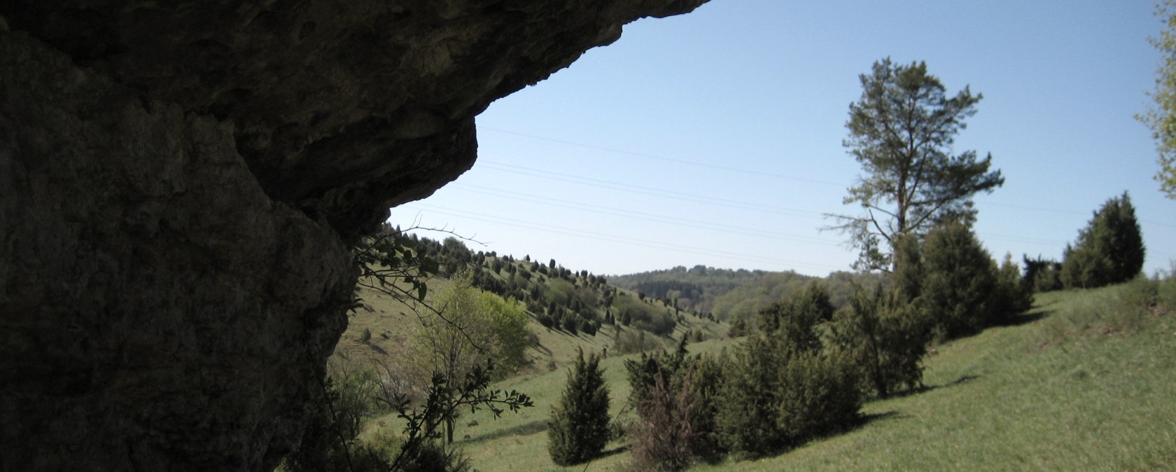 Rocky outcrop in the foreground, green hilly landscape with trees and blue sky in the background., © Touristik GmbH Gerolsteiner Land