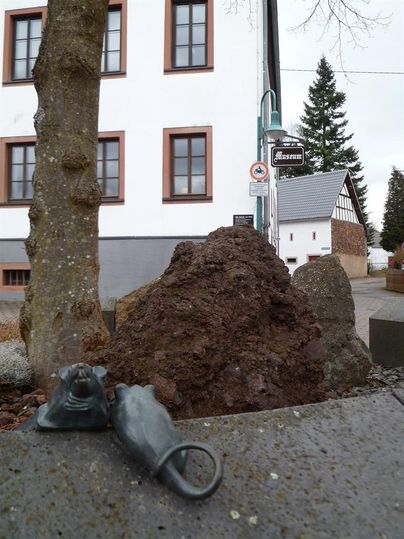 Außenansicht des Mausefallenmuseums in Neroth. Im Vordergrund eine Skulptur von zwei Mäusen, im Hintergrund ein weißes Gebäude mit braunen Fenstern.