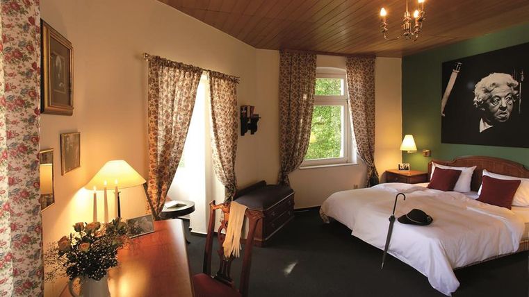 Une chambre confortable avec un grand lit et des rideaux décoratifs. Un tableau est accroché au mur, et il y a une lampe de table bien éclairée.