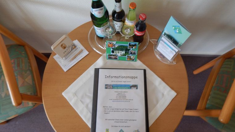 Ein Tisch mit verschiedenen Getränken, einschließlich Wasser und Limonade. Auf dem Tisch liegt ein Informationsblatt und eine kleine Karte.