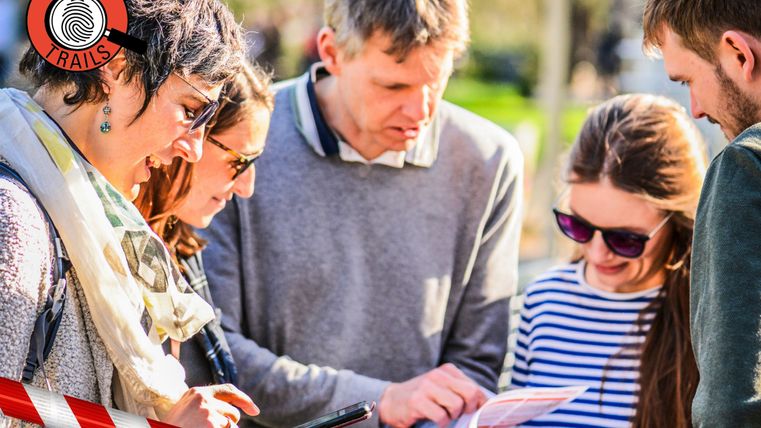 Eine Gruppe von Menschen studiert gemeinsam eine Karte im Freien während einer Krimi-Tour.