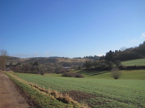 Landschaft mit grünen Feldern und Hügeln unter blauem Himmel.