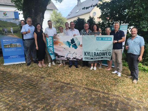 Eine Gruppe Menschen halten gemeinsam einen Veranstaltungsbanner zum Radaktionstag Grenzenlos Kyllradweg 2026 hoch.