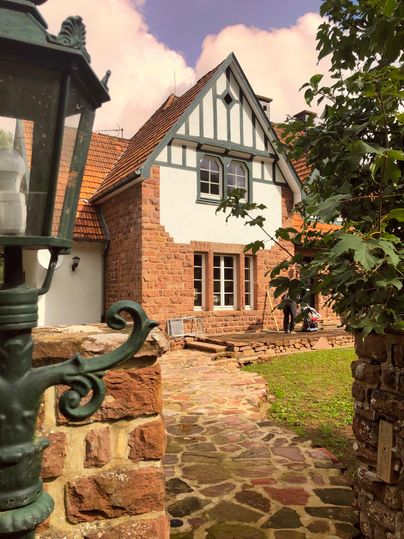 Une charmante maison à colombages avec un jardin bien entretenu. Au premier plan, il y a une lanterne et le chemin qui mène à la maison.