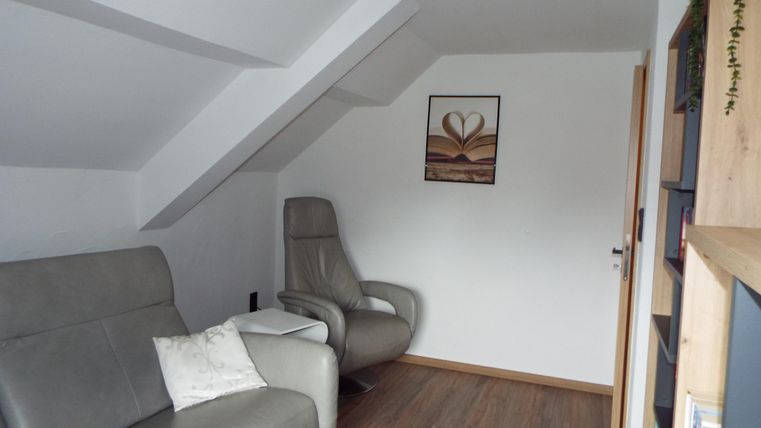 Ein gemütlicher Raum mit zwei bequemen Sesseln und einem kleinen Tisch. An der Wand hängt ein Bild mit einem Herz-Motiv.