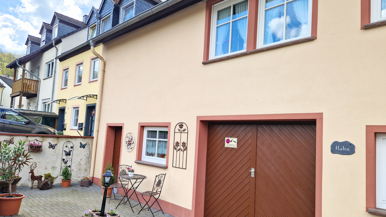 Une maison charmante avec une entrée élégante et un petit coin salon. La façade est lumineuse et accueillante, entourée de plantes et d'œuvres d'art.