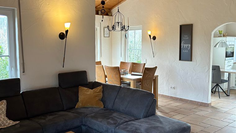 Un salon confortable avec un canapé gris foncé et une table en bois. La pièce a de hauts plafonds et de grandes fenêtres qui laissent entrer beaucoup de lumière.