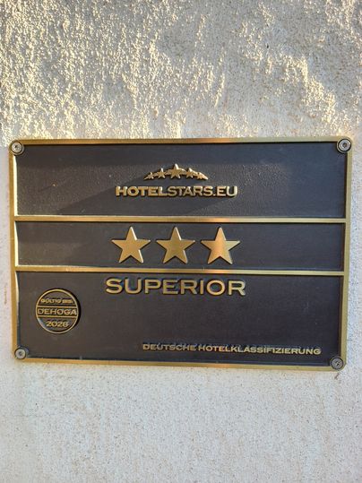 Eine Stahlplakette an einer Auswand von hotelstars.eu mit den verdienten 3 Sternen und dem Zusatz Superior. Gültig bis 2028. 