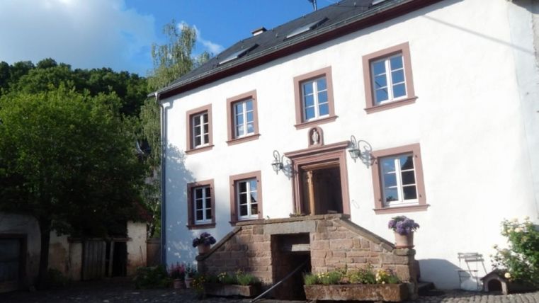 weißes, restauriertes ehemaliges Bauernhaus mit Treppe vor dem Eingang