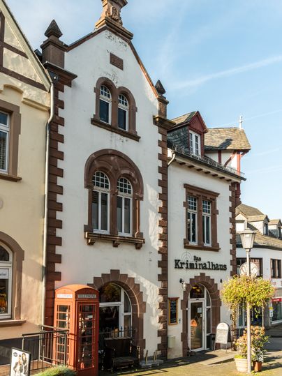 Historisches Gebäude mit roter Telefonzelle und Schild 'Das Kriminalhaus' in Hillesheim.