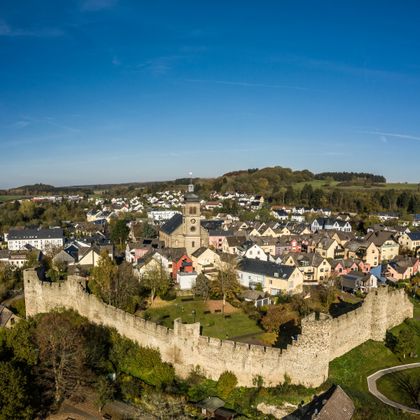 Luftaufnahme von Hillesheim mit Stadtmauer und Kirche im Zentrum.