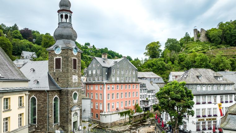 Zicht op het oude stadscentrum van Monschau met het opvallende Rode Huis en een kerk op de voorgrond.