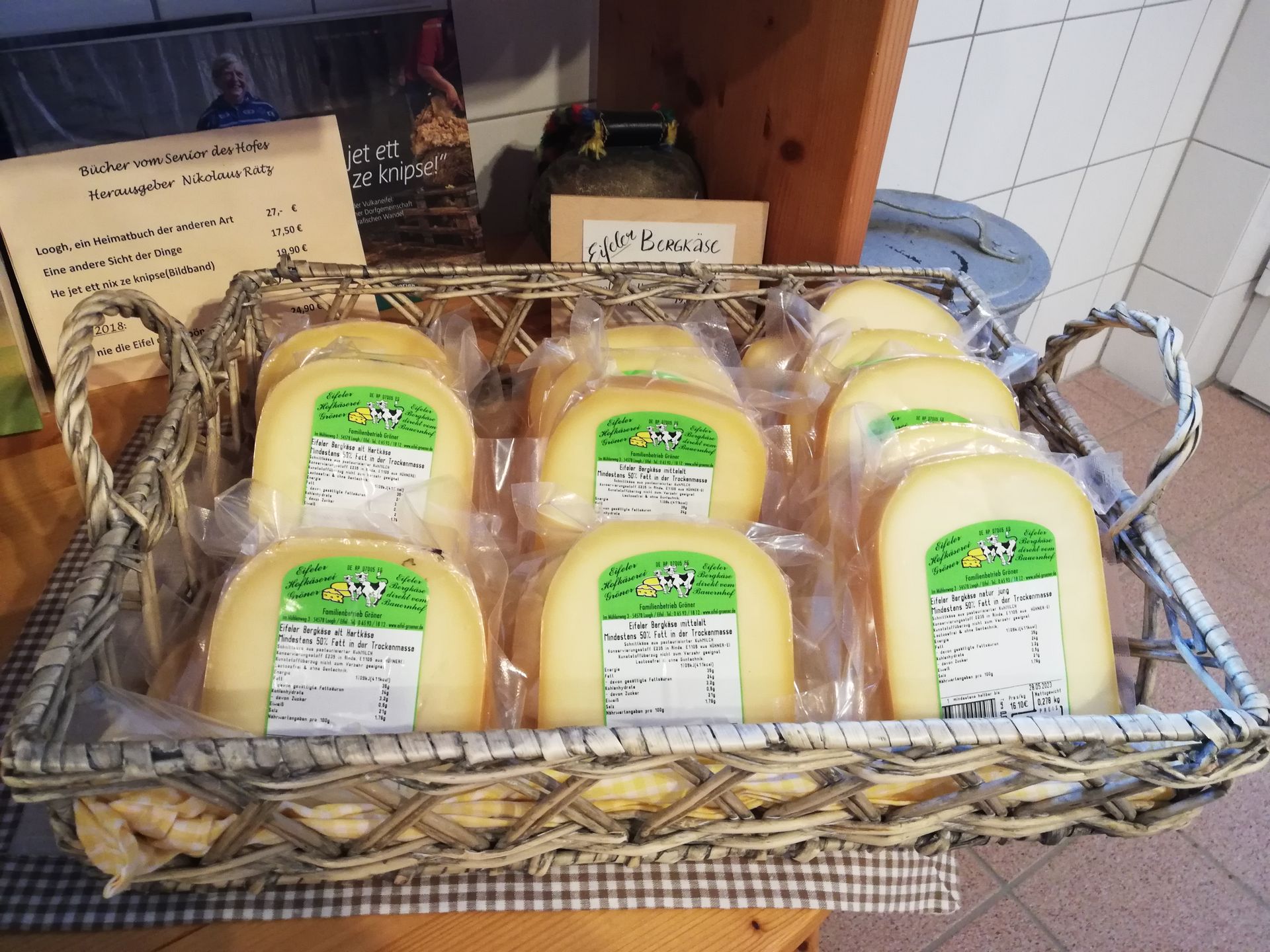 Ein Holzkorb, gefüllt mit einigen eingeschweißten Käsestücken der Marke Gröner Hof.