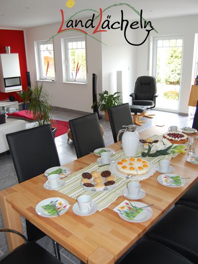 Ein schön gedeckter Tisch in einem modernen Raum. Auf dem Tisch liegen verschiedene Köstlichkeiten und Getränke.