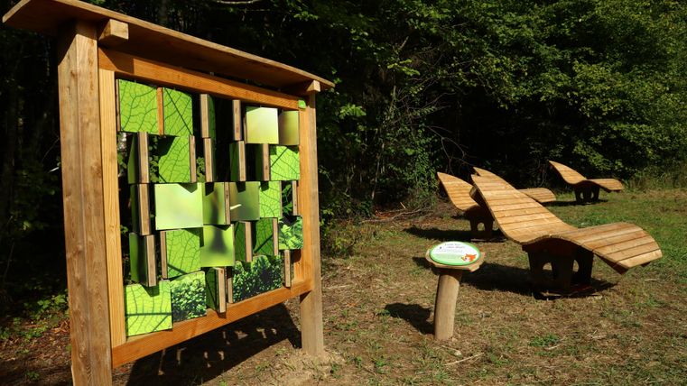 Man sieht eine Station wo Kinder ein Bildrätsel lösen müssen. Im Hintergrund befinden sich Liegebänke zum ausruhen in der Sonne