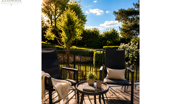 Cozy seating area on a terrace with a view of the greenery. Sunny weather and blue skies create an inviting atmosphere.