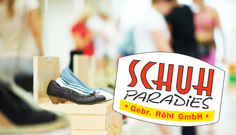 Verschiedene Damenschuhe auf Kartons und personen verschwommen im Hintergrund. Das Logo des Schuhparadies im Vordergrund.