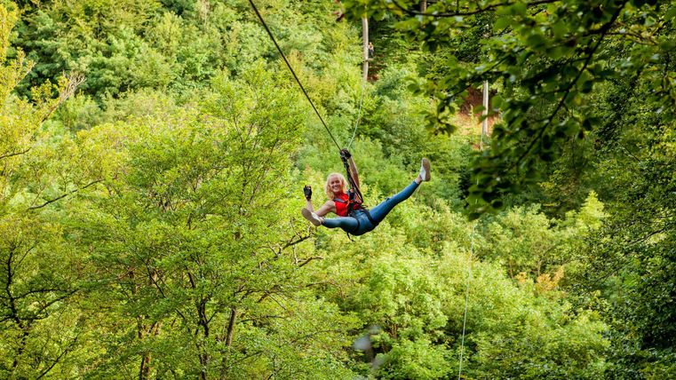 Frau, die an einer Zipline im Wald hängt