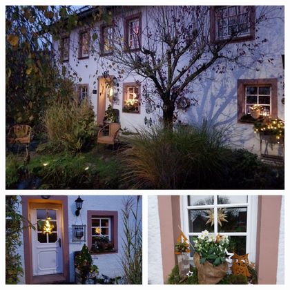 Een mooi huis met feestelijke verlichting en een gezellige tuin. Er zijn bloemen en een versierde voordeur.