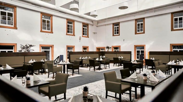 Ein elegantes Restaurant mit modernen Sitzbereichen und großen Fenstern. Die Atmosphäre ist hell und einladend, ideal für ein angenehmes Essen.