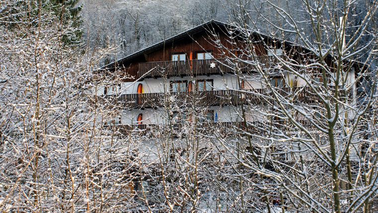 Un bâtiment semblable à un chalet dans un paysage enneigé. Les arbres sont recouverts de neige fraîche.