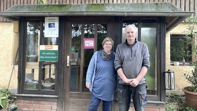 Ein Mann und eine Frau stehen vor einem Gebäude und lächeln in die Kamera.