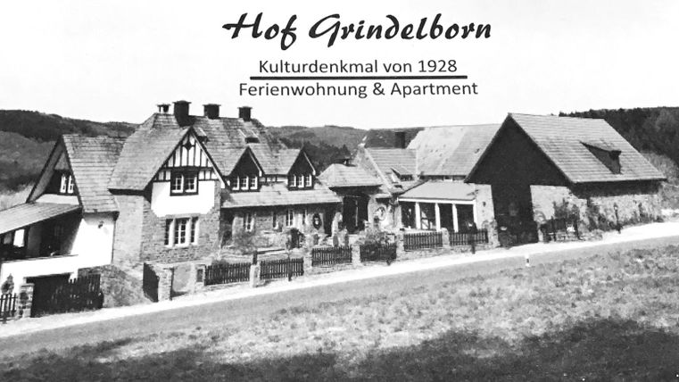 Un bâtiment historique avec une architecture traditionnelle, entouré d'un paysage verdoyant. L'image montre Hof Grindelborn, un monument culturel de 1928.