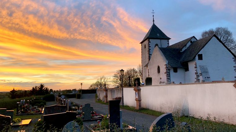 Wehrkirche bei Sonnenuntergang mit Friedhof im Vordergrund.