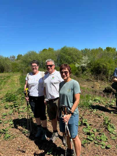 3 in Wanderkleidung gekleidete Personen stehen lachend nebeneinander
